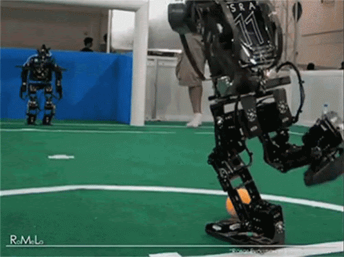 Humanoid robots attempting to kick a soccer ball in an indoor testing environment