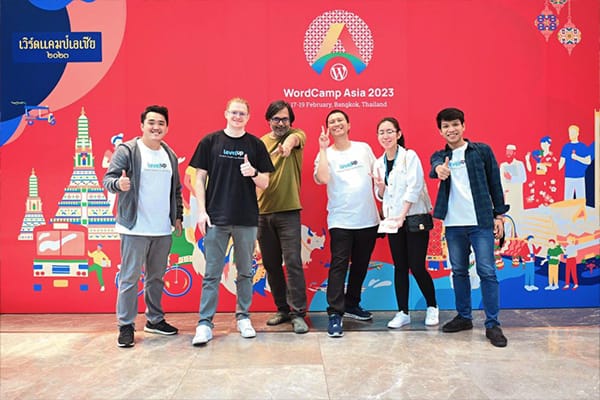 LevelUp team members posing at a WordCamp Asia 2023 event, smiling in front of a colorful background with WordCamp Asia branding.