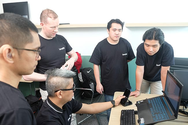 A group of LevelUp team members gathered around a laptop, reviewing financial reports and discussing strategic decisions in a collaborative setting.