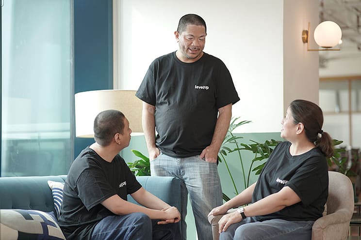 Three LevelUp team members having a conversation in a relaxed office environment.