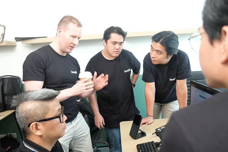 A group of individuals wearing black LevelUp t-shirts in a discussion, emphasizing teamwork and collaboration in offshore staffing.