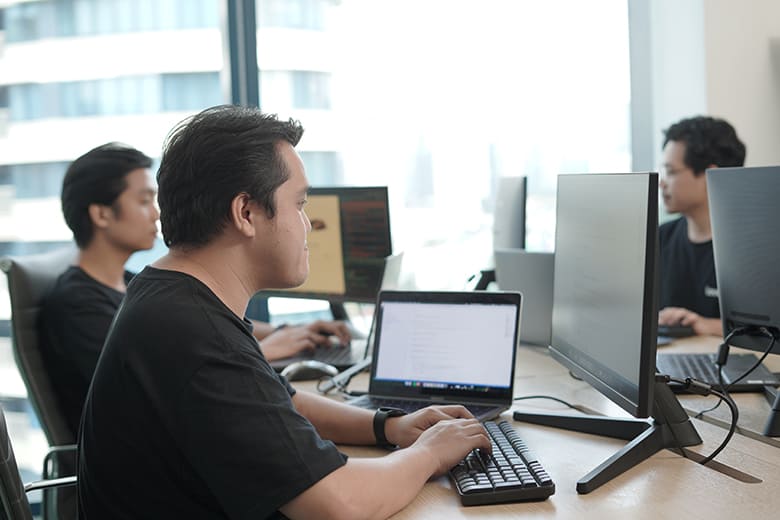 IT support technicians at their desks, collaborating and working on computer systems in a modern office setting