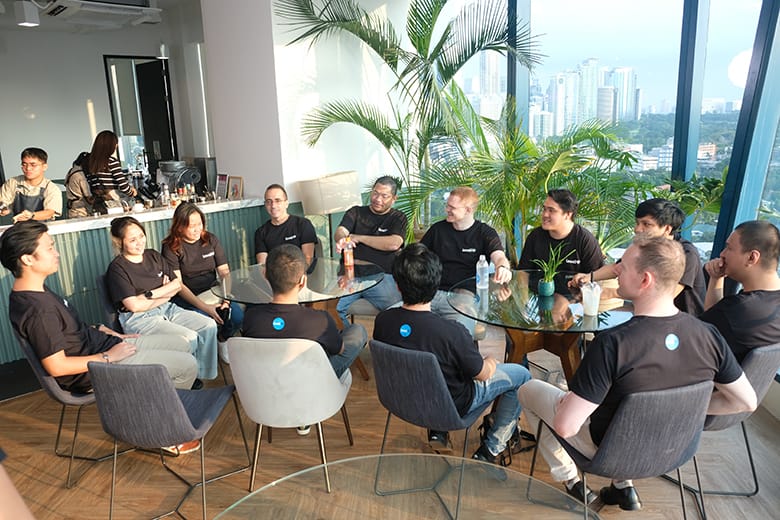LevelUp team members in black shirts engaging in collaborative discussion around a table.