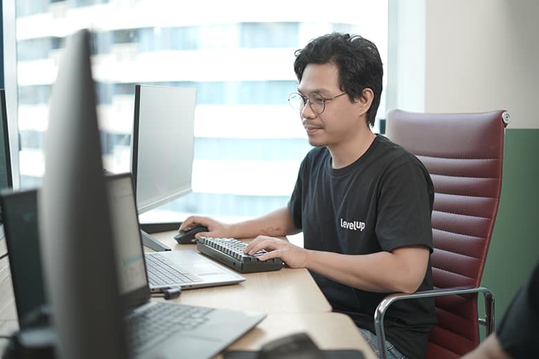 VA_Photo A virtual assistant working at a desk with multiple screens, typing on a keyboard and providing support.