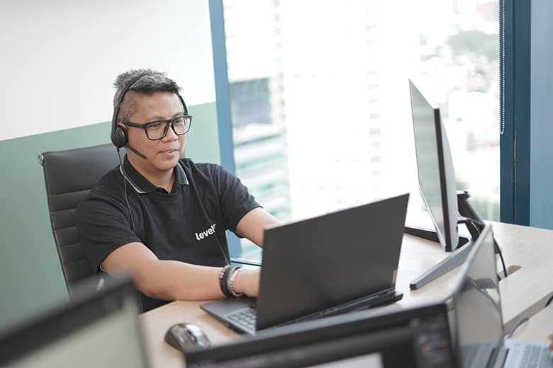 GLB06448 - optimized A professional in a black shirt wearing a headset while working on a laptop, illustrating focus and expertise in managing offshore digital marketing tasks.