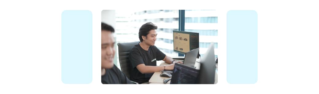 Two men working at computers in a modern office, representing offshore team members.