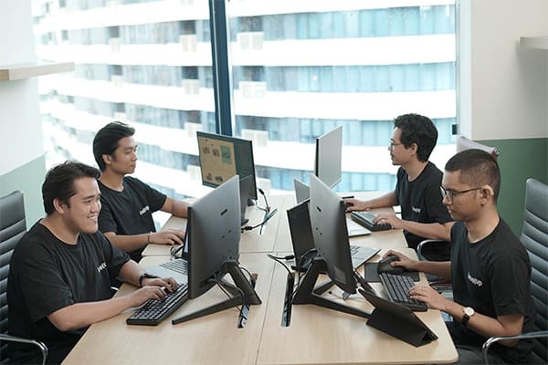 LevelUp team members sitting at desks in a modern office, working collaboratively on desktop computers.