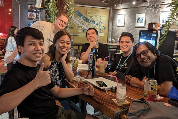 LevelUp team members in casual attire enjoying a meal together in a restaurant, smiling and posing for the camera with drinks on the table.