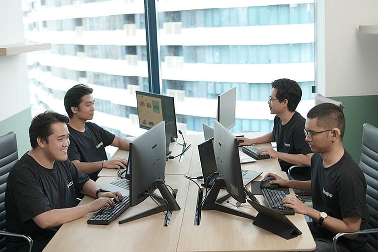 Chat Support Agent - Working Chat support agents working at individual computers in a modern office, facing each other across a shared workspace