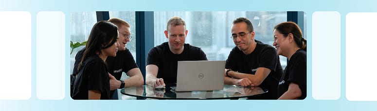 Collaboration Among the LevelUp Recruitment Team LevelUp recruitment team gathered around a laptop, discussing specialized hiring strategies to identify top offshore talent.