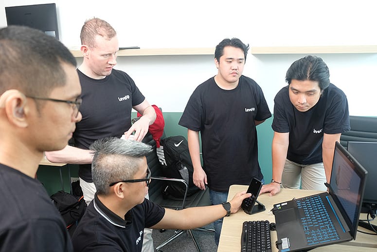 LevelUp team members gathered around a laptop, collaborating on tools and processes.