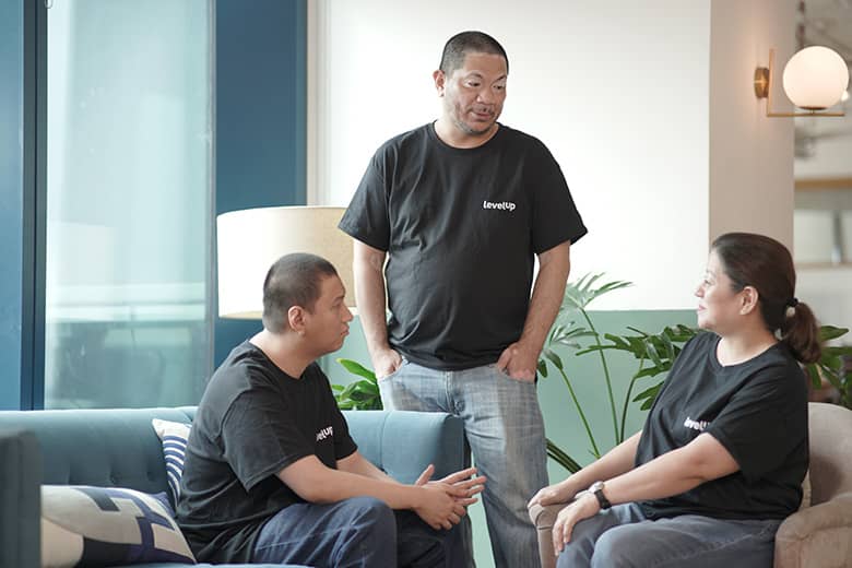 A team of three individuals engaged in a collaborative discussion in a modern office environment.