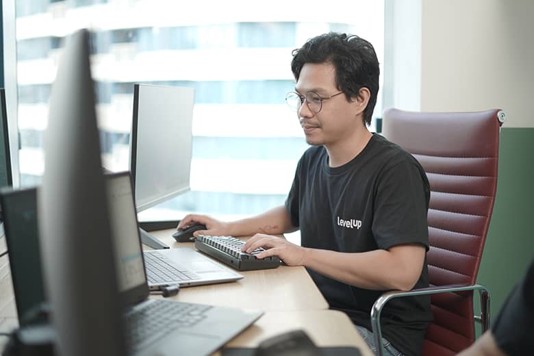 A virtual assistant working at a desk with multiple screens, typing on a keyboard and providing support.