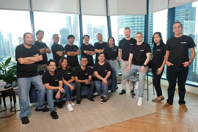 LevelUp Team LevelUp team members posing together in a modern office with a city view in the background.