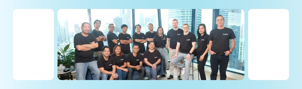 The LevelUp Philippines software development team poses together in an office with city views, representing the strength and stability of long-term offshore partnerships.