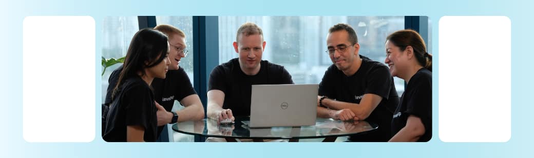 A team sitting together at a table working on a laptop.